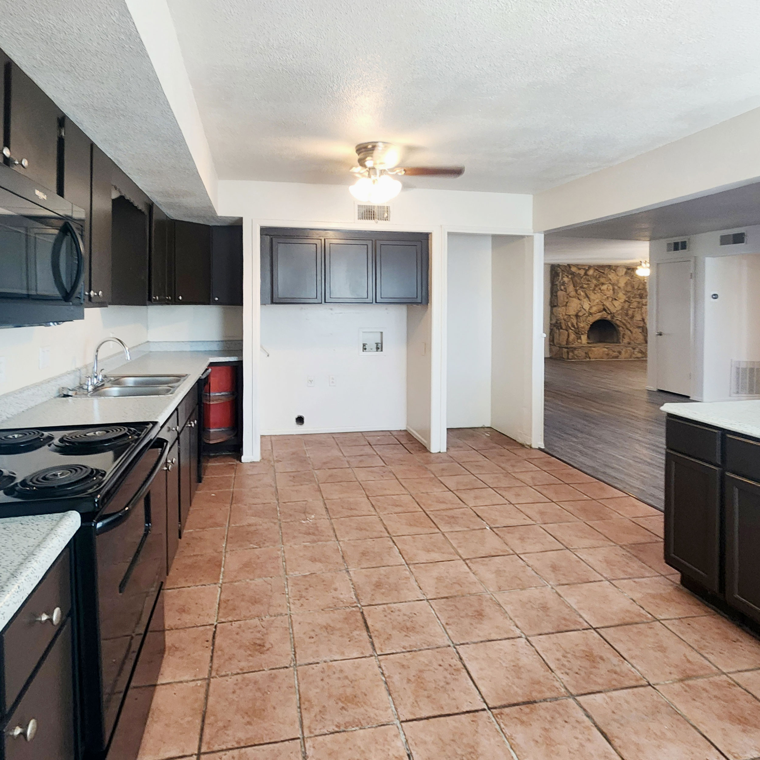 Kitchen with dark cabinets, ample counter space and an opening to the living room