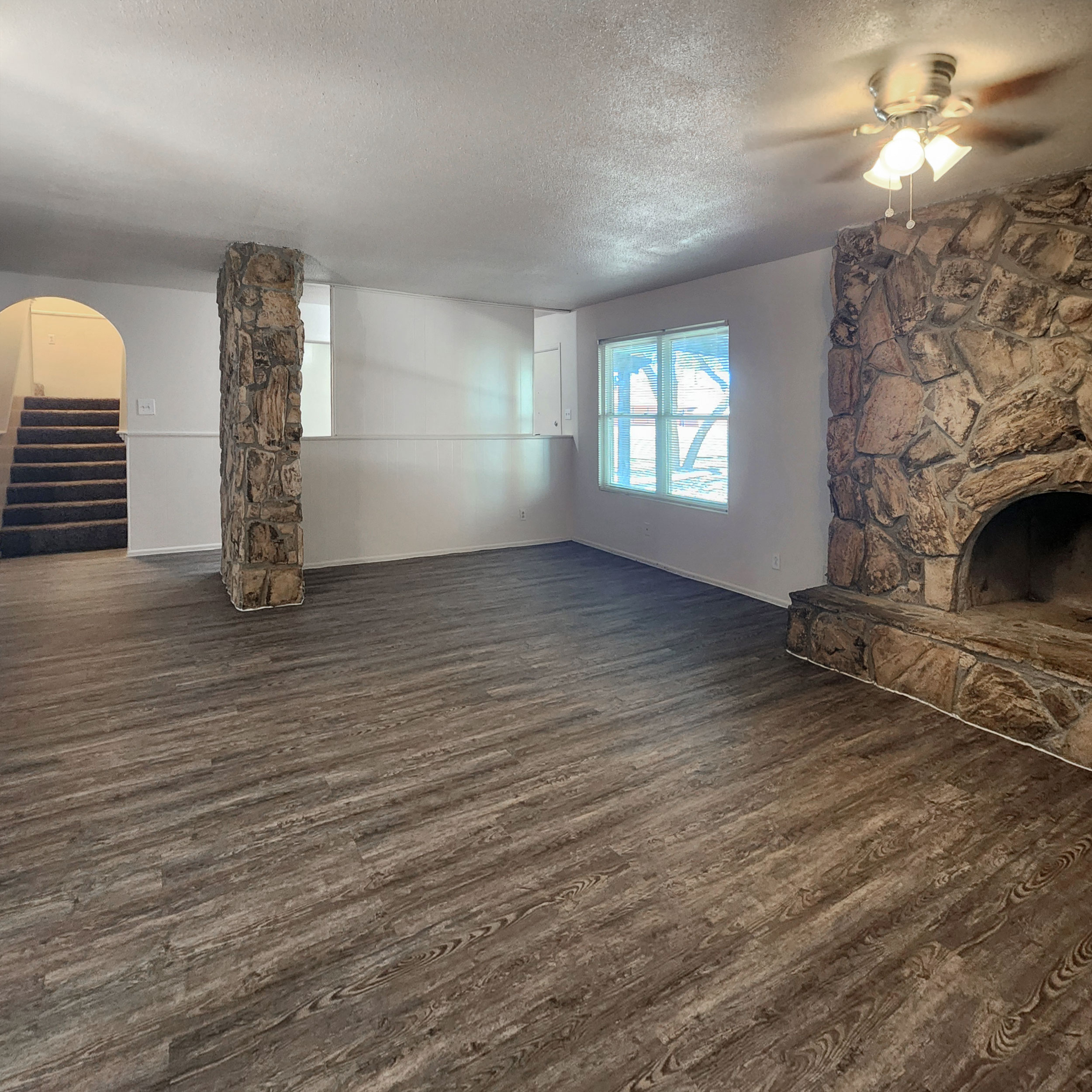Spacious four-bedroom apartment living room with stone fireplace and wood-look flooring